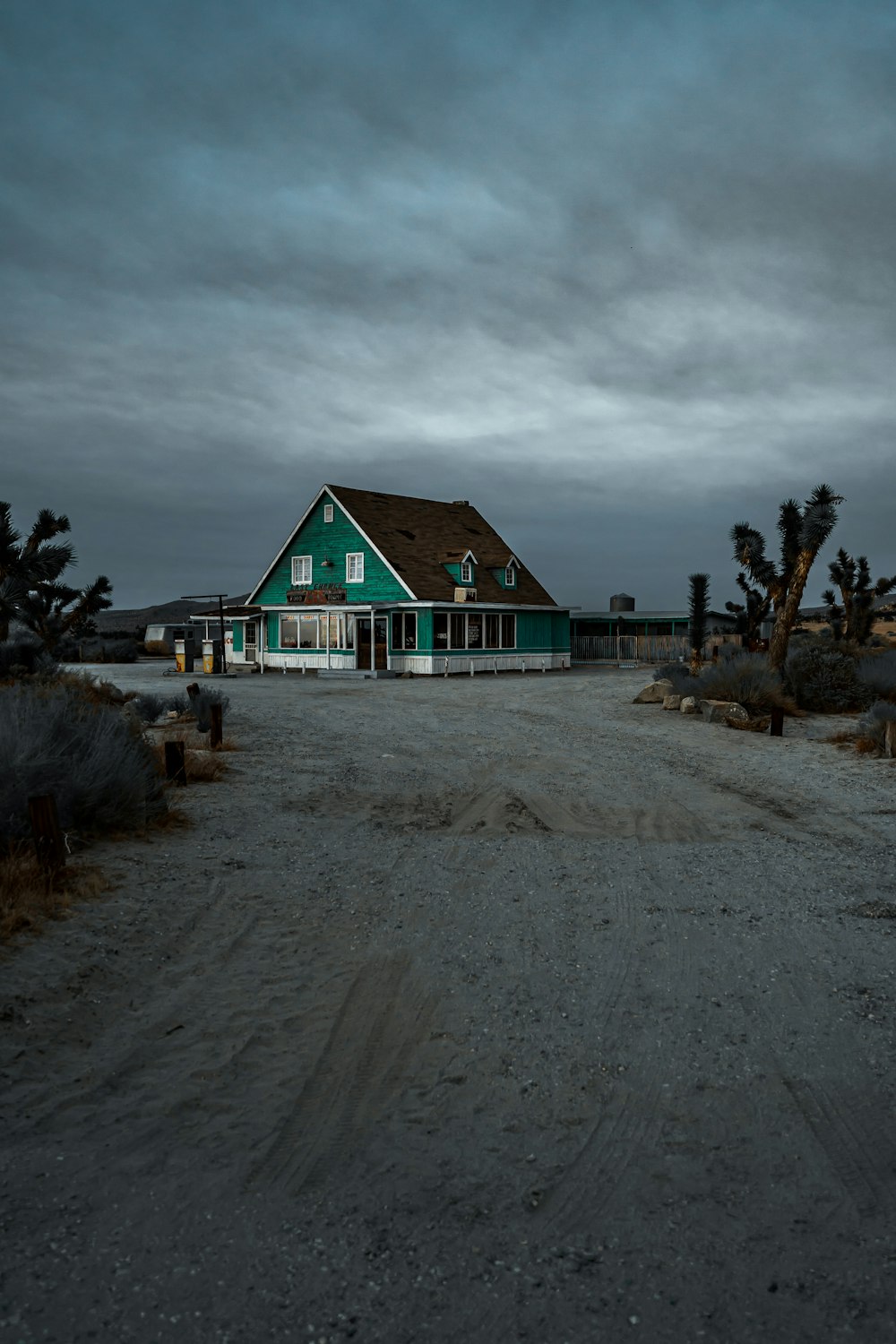 green and white wooden house near trees under white clouds during daytime