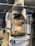 A store mannequin is dressed in a casual outfit consisting of a graphic t-shirt with a photo print of a person, a dark baseball cap with writing that says 'go play outside,' and a knit scarf draped over the shoulders. The store's name, HIGHST, is displayed behind the mannequin.