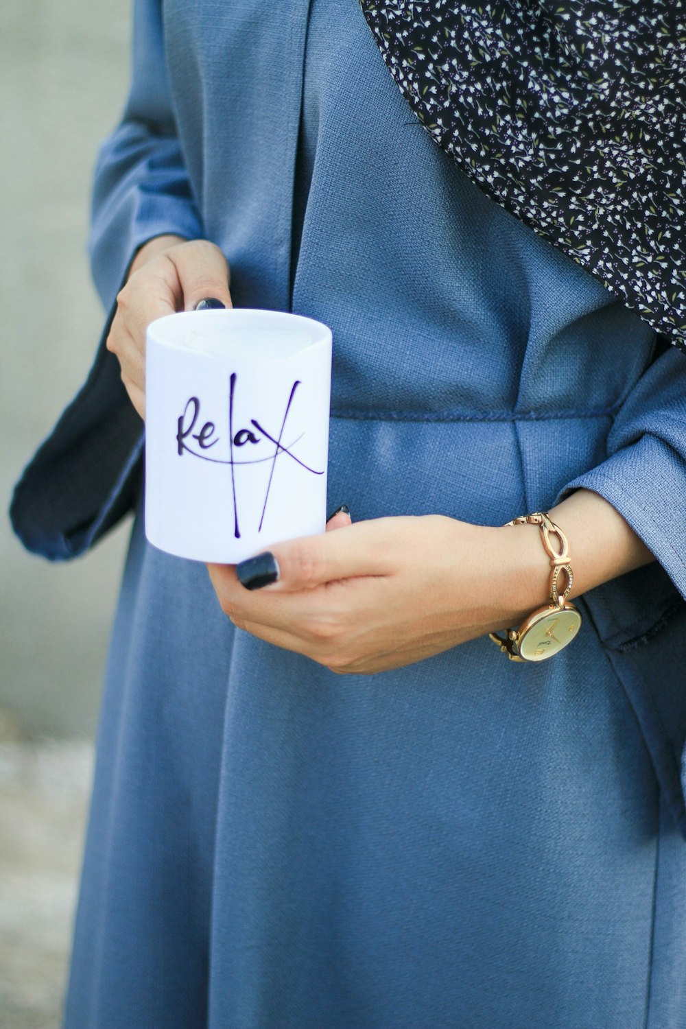 person in blue coat holding white ceramic mug