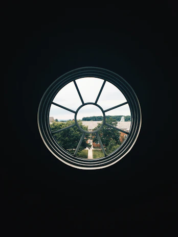 A scenic view from a large window overlooking a peaceful neighborhood street framed by trees.