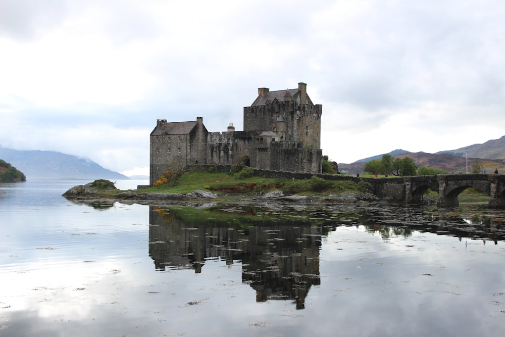 gray concrete castle on body of water under white clouds during daytime