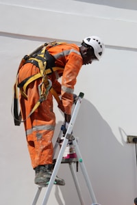 man in orange jacket and white helmet holding white and black stick