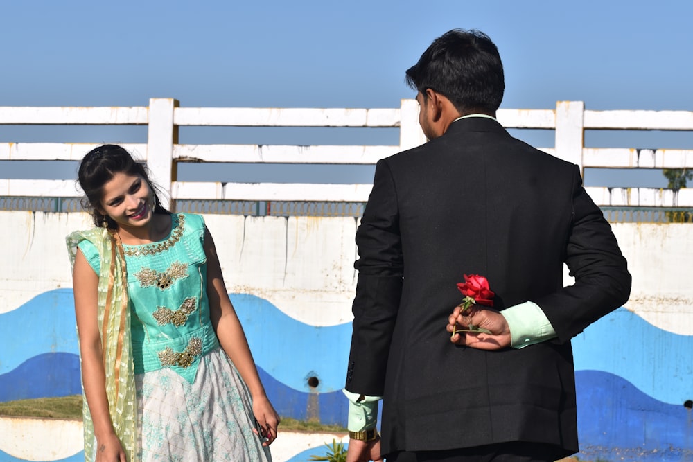 man in black suit jacket holding red rose bouquet