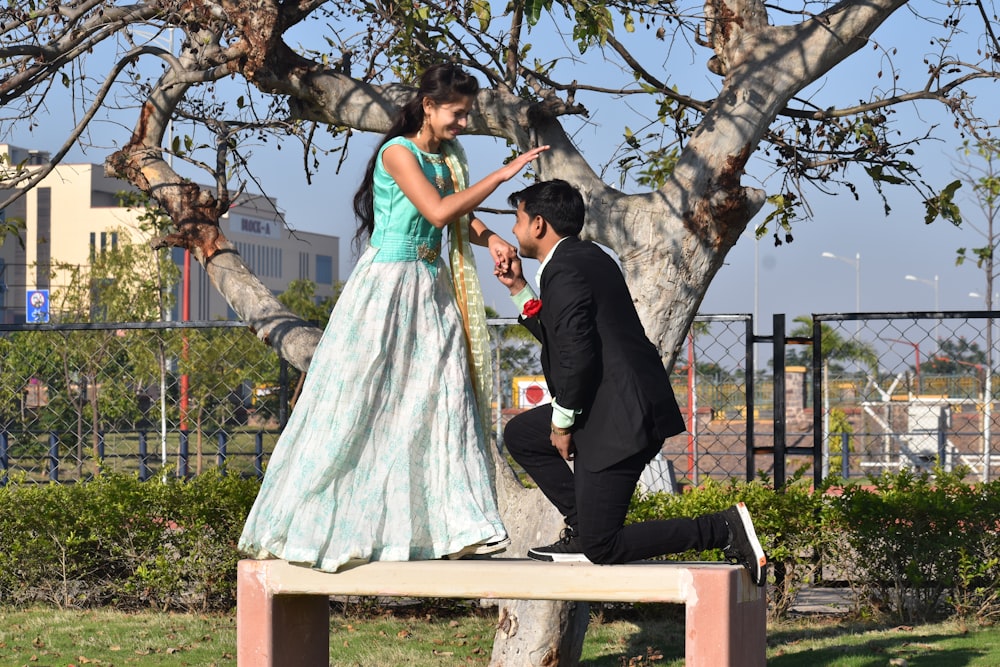 man and woman kissing on brown wooden bench during daytime