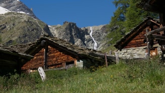Cozy cabin exterior beside a glistening 12-foot waterfall under a clear blue sky.