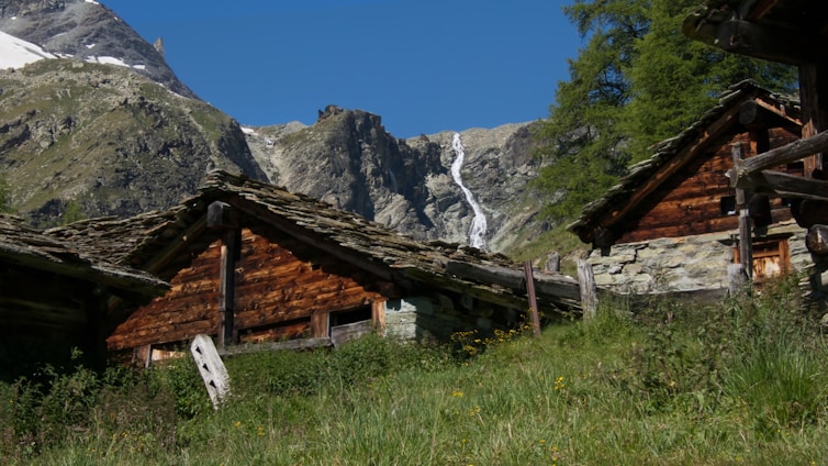 Cozy cabin exterior beside a glistening 12-foot waterfall under a clear blue sky.