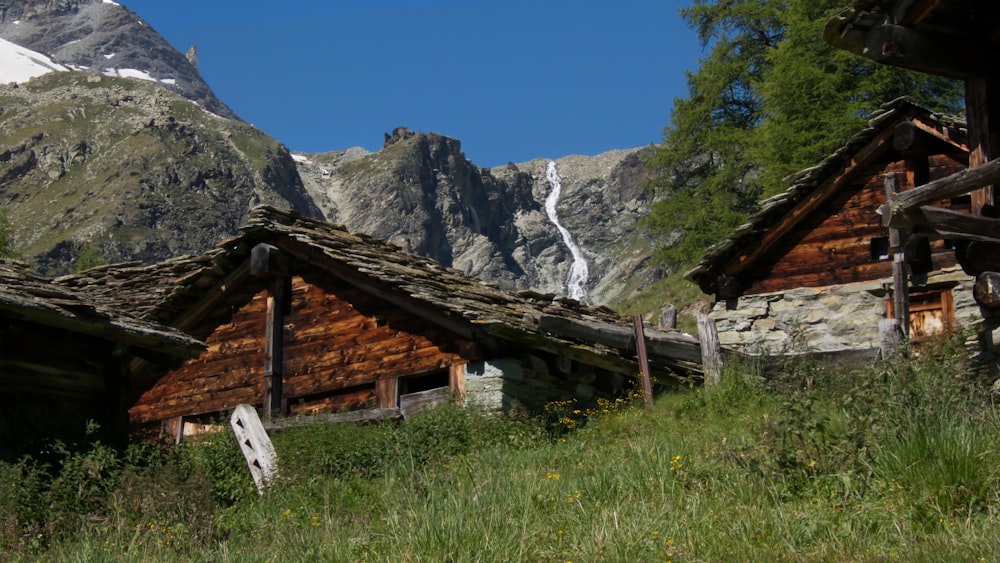 Casa di legno marrone sul campo di erba verde vicino alla montagna rocciosa grigia durante il giorno