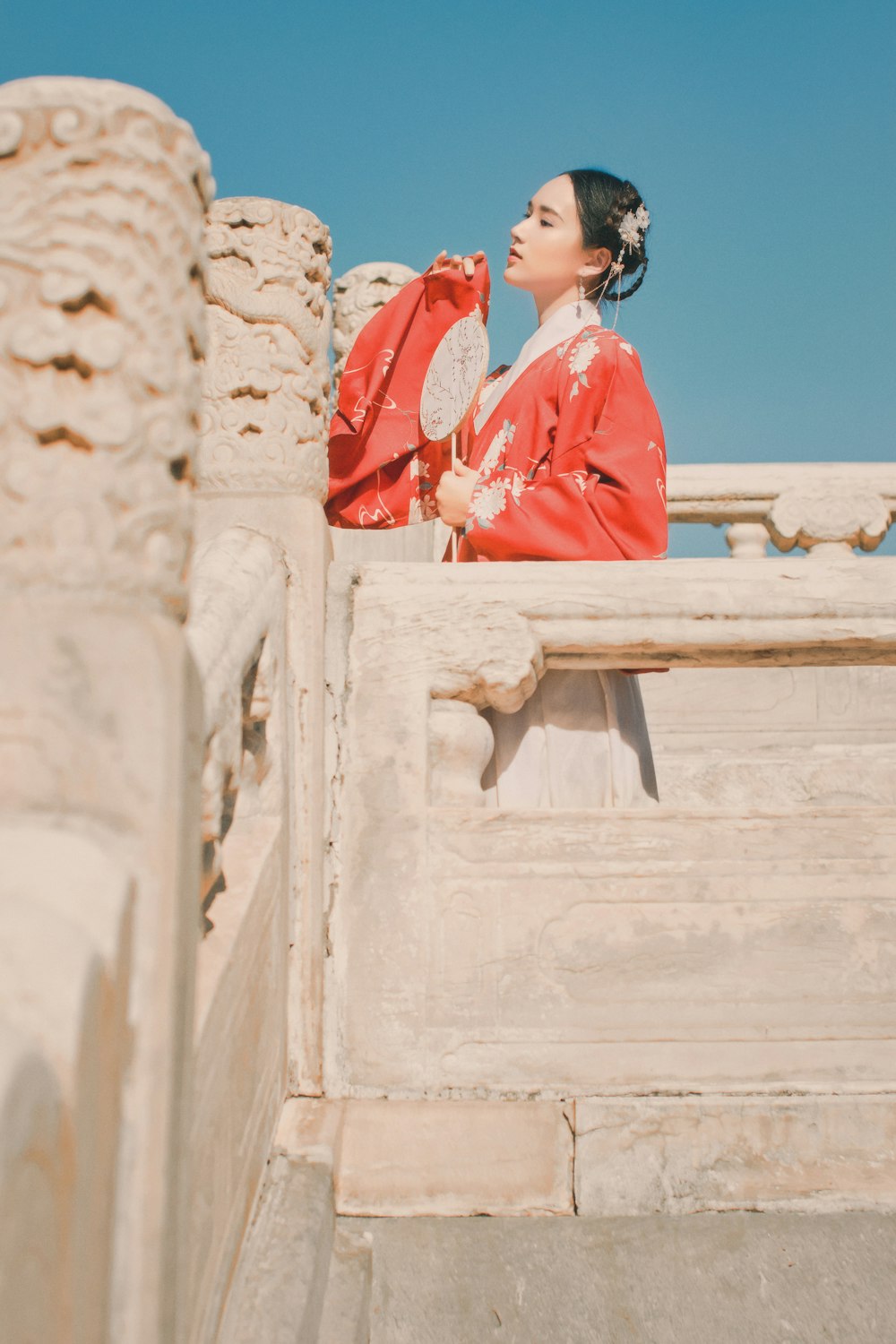 woman in red long sleeve shirt standing on white concrete wall during daytime