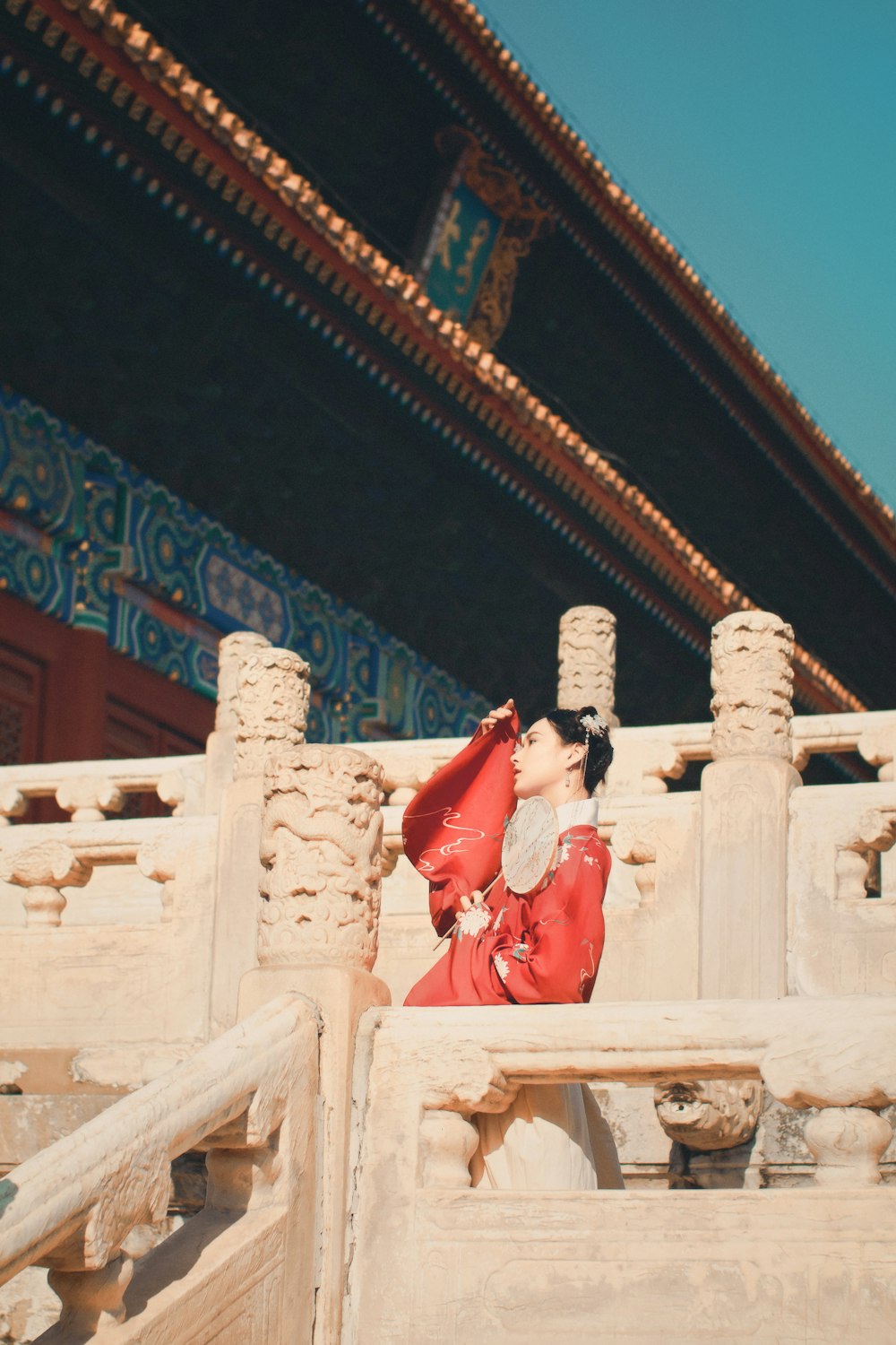 하얀 콘크리트 벤치에 앉아 빨간 드레스를 입은 여자