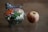 A fresh salad in a clear plastic container, featuring ingredients like shredded carrots, lettuce, cheese cubes, sliced egg, and deli meat. Next to it is an apple, light red with a hint of yellow, resting on a flat surface.