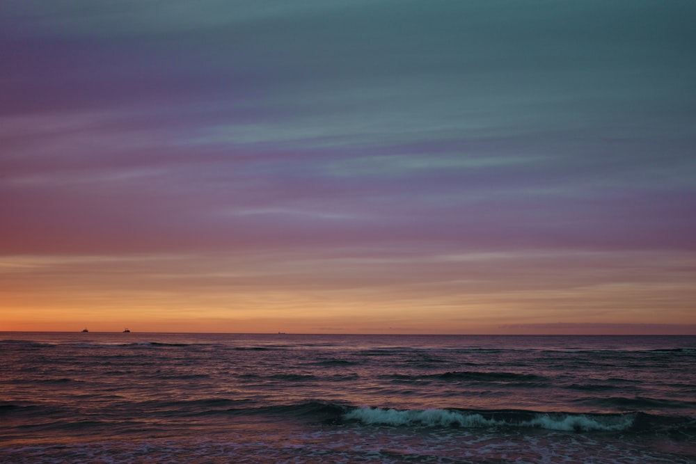 ocean waves crashing on shore during sunset