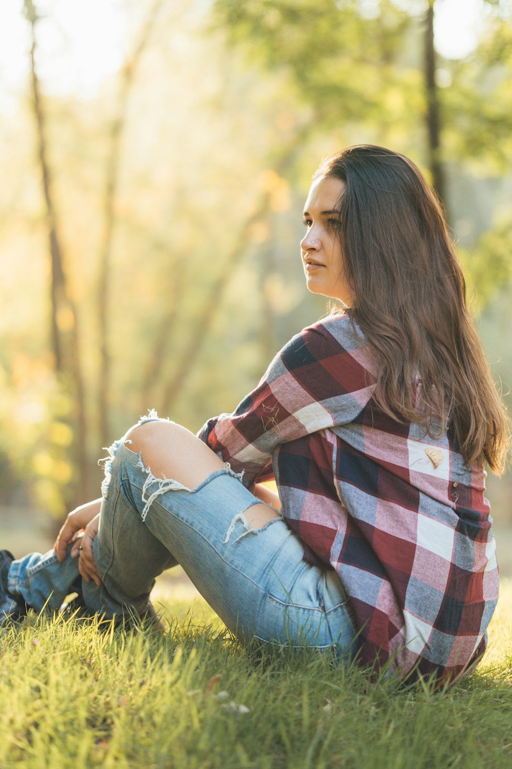 woman in blue denim jeans sitting on green grass during daytime