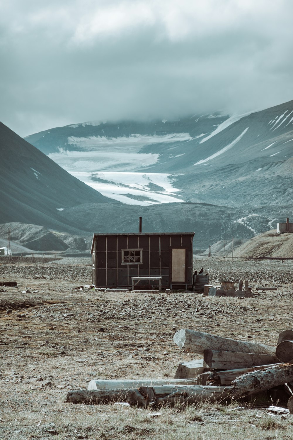 brown wooden house near snow covered mountain during daytime