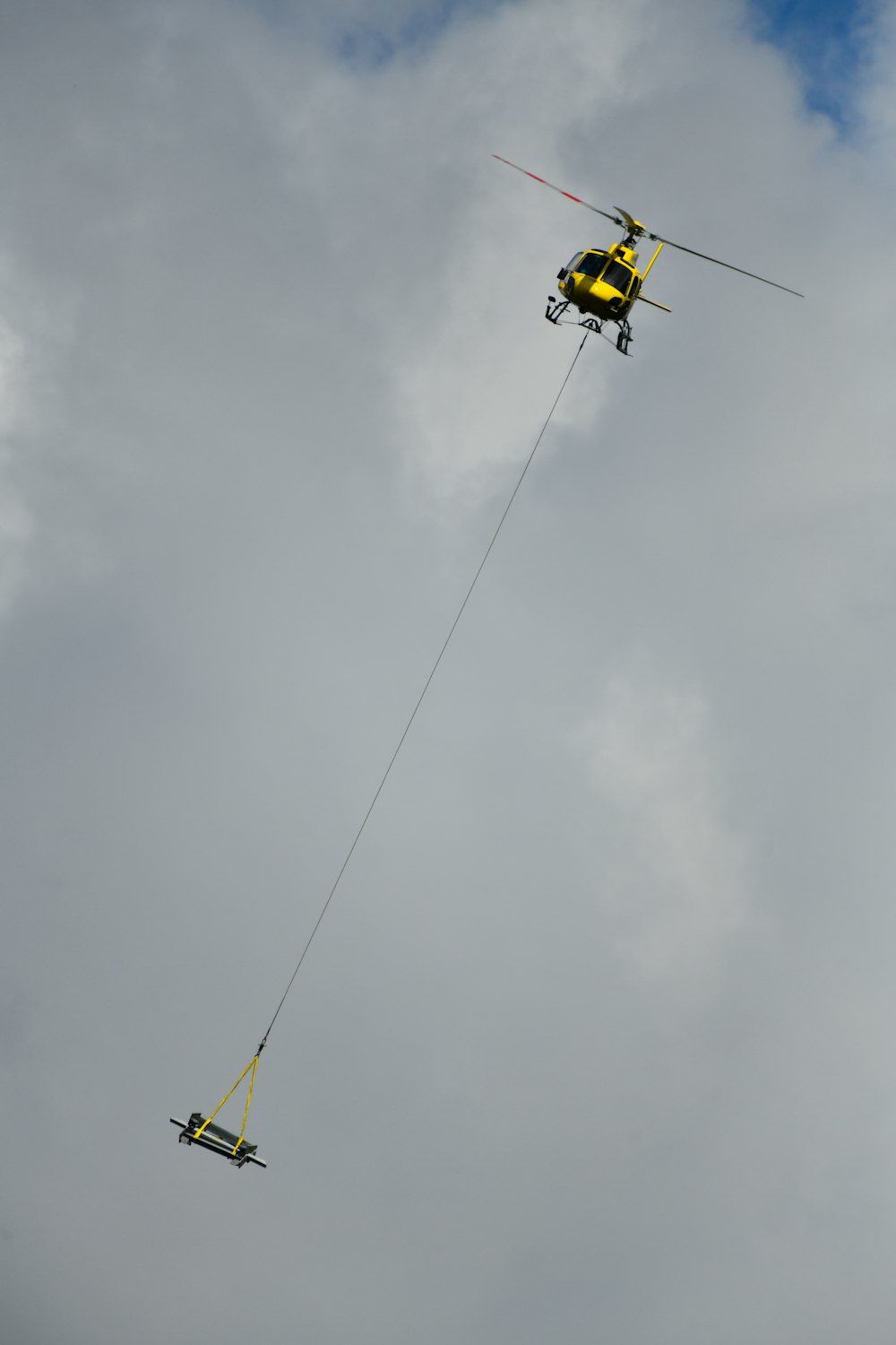 gelber und schwarzer Hubschrauber, der tagsüber unter weißen Wolken fliegt