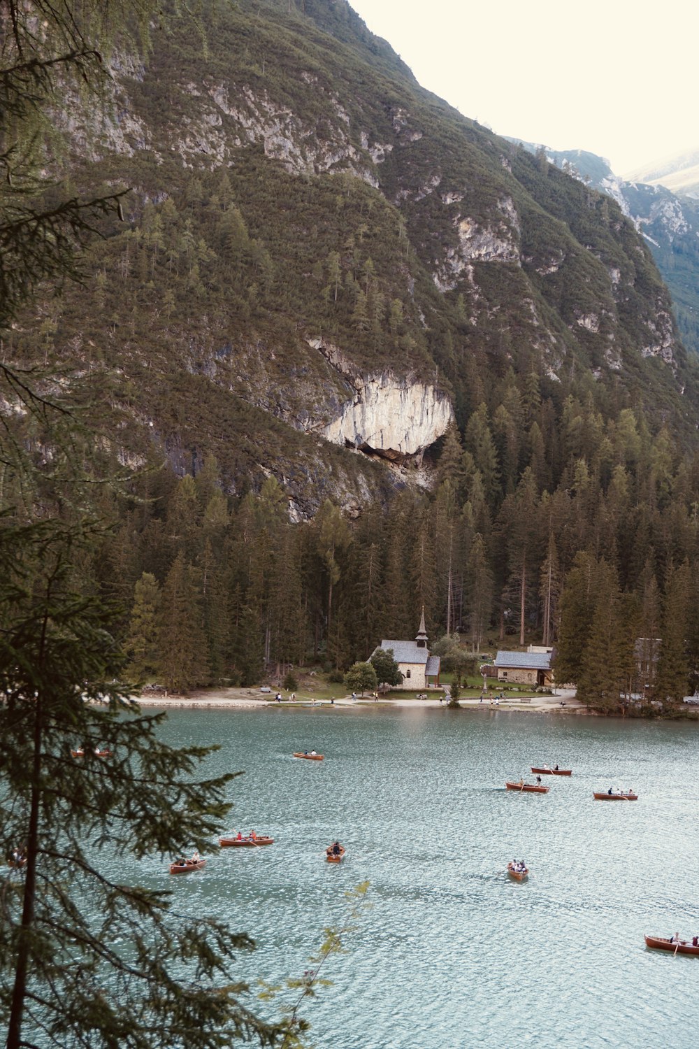 white and red boat on water near green trees and mountain during daytime