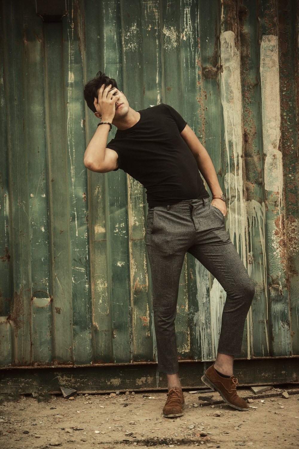 woman in black shirt and gray denim jeans leaning on green wooden wall