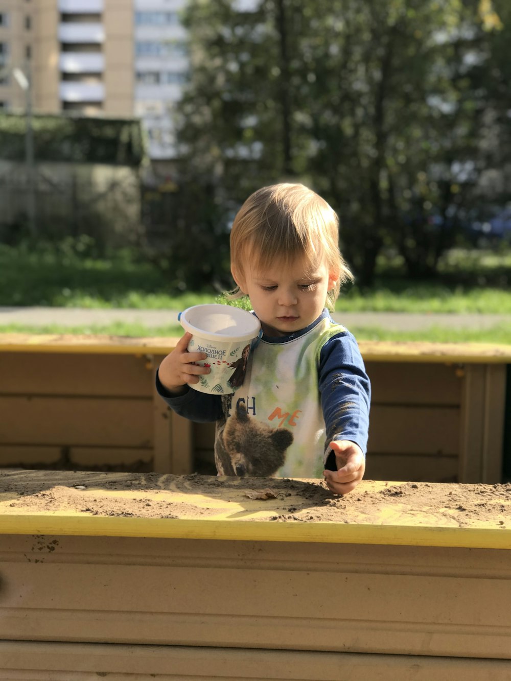 child in blue and white long sleeve shirt feeding a gray rabbit