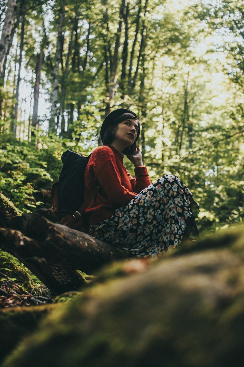 woman in red jacket sitting on tree log