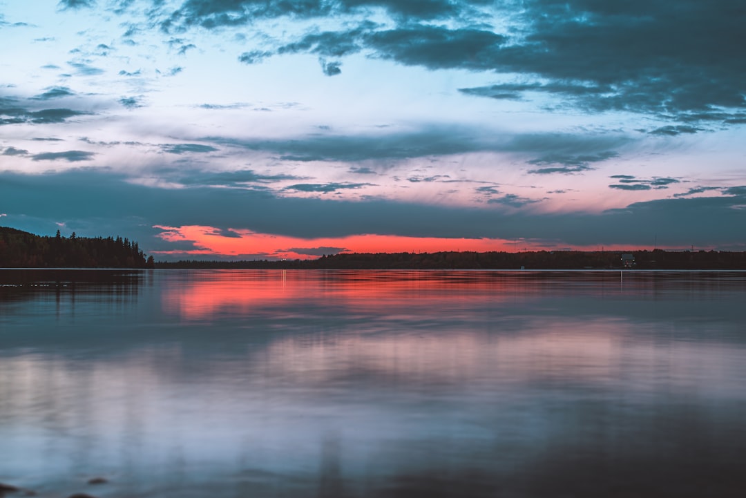 body of water under cloudy sky during sunset