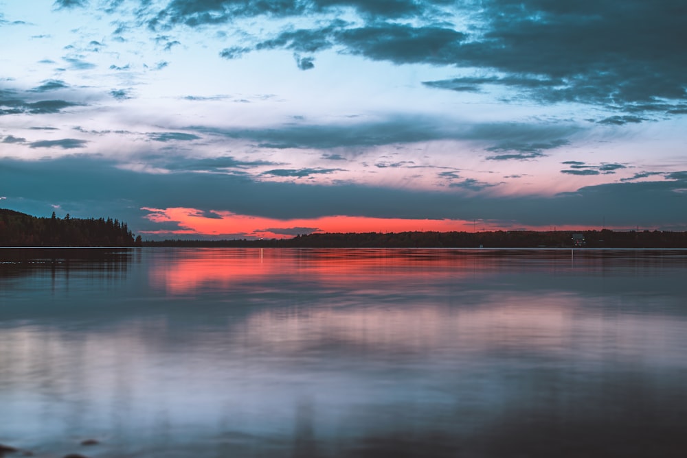 body of water under cloudy sky during sunset