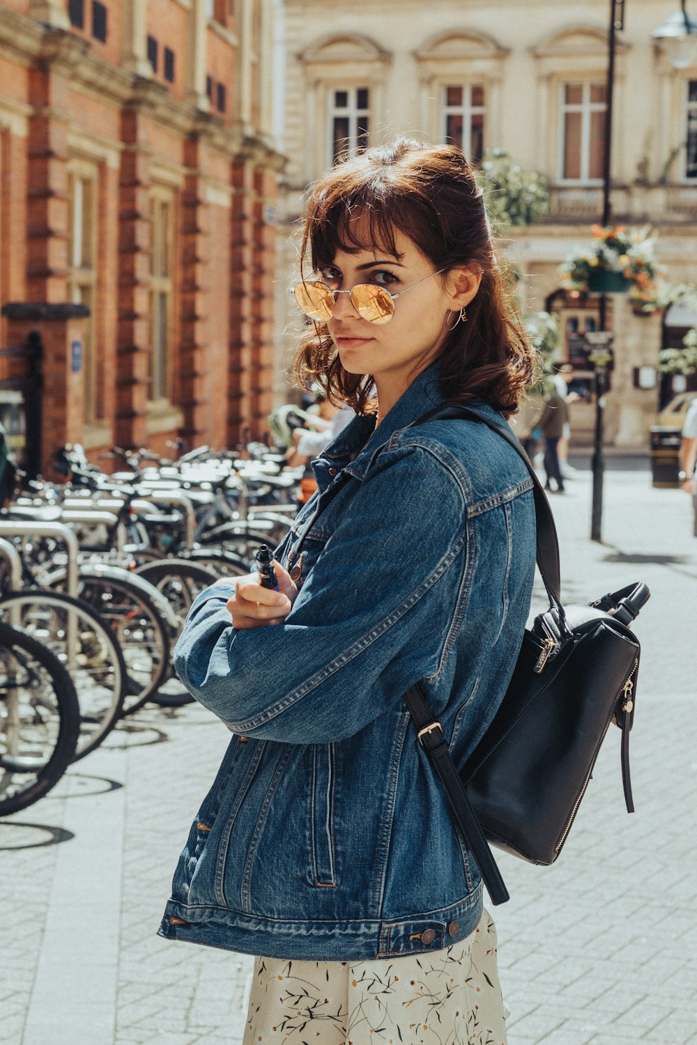 woman in blue denim jacket and blue denim jacket standing on sidewalk during daytime