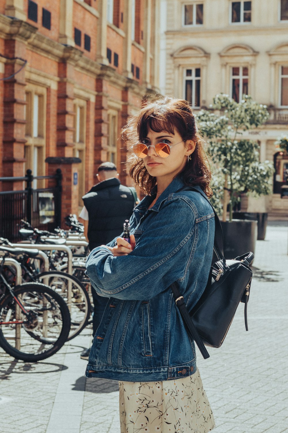 Donna in giacca di jeans blu in piedi accanto alla bicicletta durante il giorno