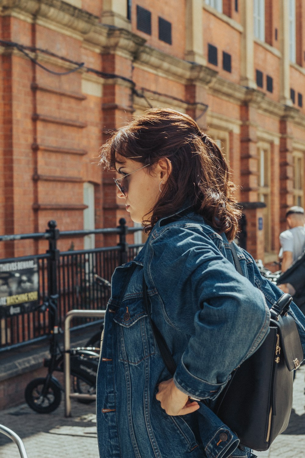 woman in blue denim jacket standing near black metal fence during daytime