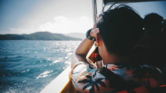 woman in white and blue floral shirt sitting on boat during daytime