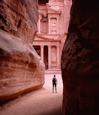 person walking on pathway between brown rock formation during daytime