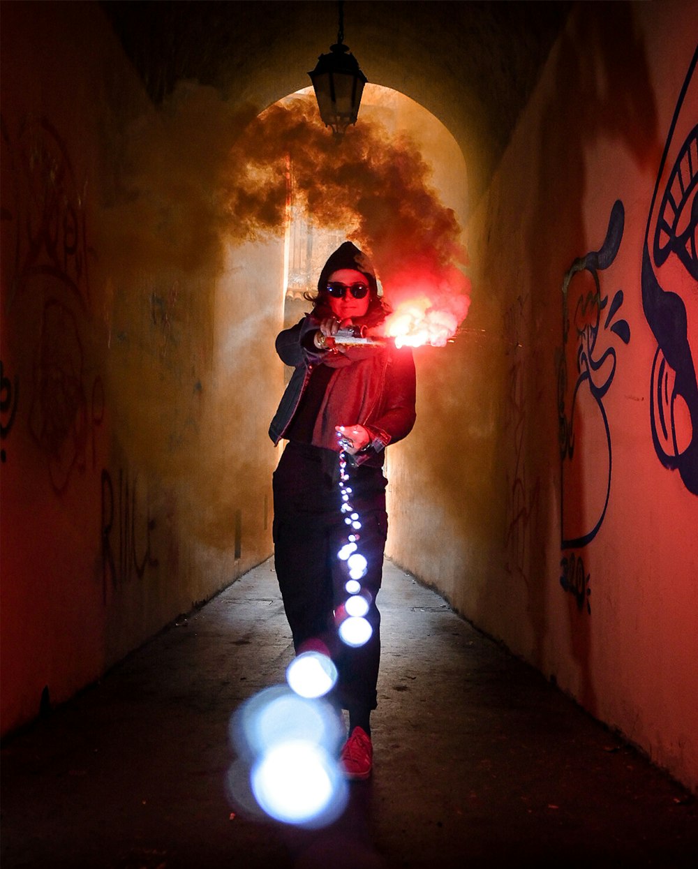 man in black jacket standing in front of yellow and red smoke