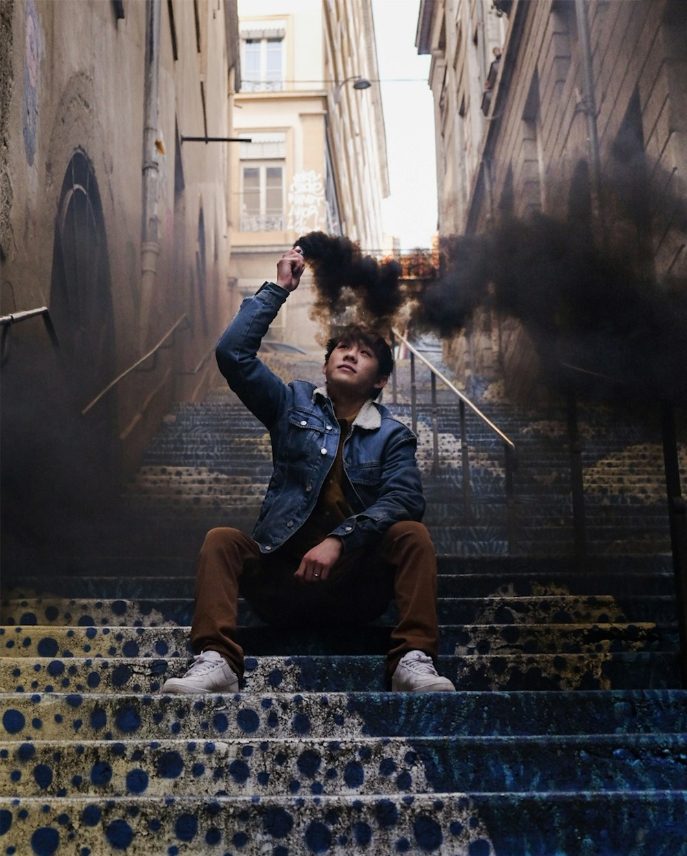 man in blue denim jacket sitting on concrete bench