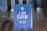 A blue table sign displays the text 'I AM CLEAN' with additional smaller text stating 'This table has been sanitised and is ready to use.' The sign includes a circular logo at the top depicting a hand with bubbles.