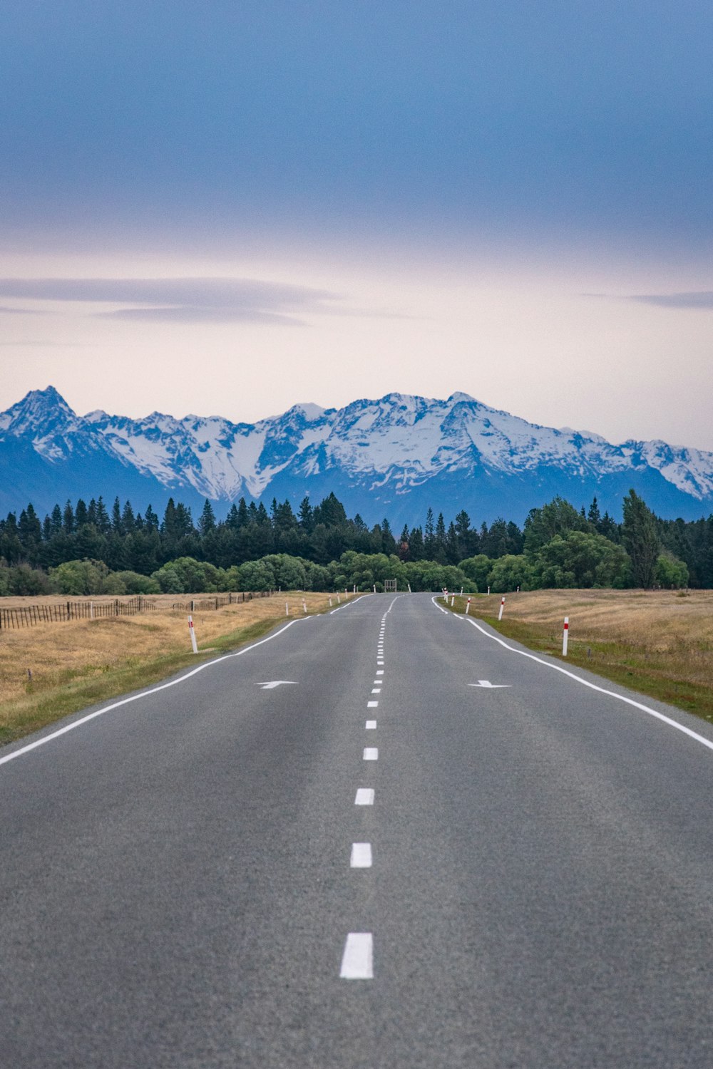 gray concrete road near green grass field and mountain during daytime