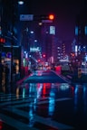 cars on road between high rise buildings during night time