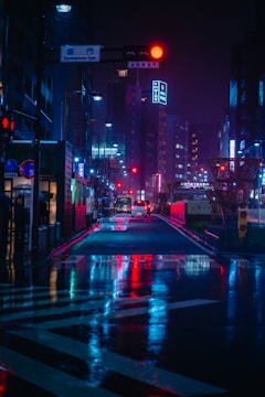 futuristic Asian city at night with cars on road between high rise buildings