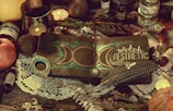 A mystical setup featuring a notebook with a crescent moon design and the words 'witch aesthetic' on the cover. The notebook is adorned with a decorative feather, a crystal, and a pendant. Surrounding objects include candles, an apple, various potion bottles, and a lace cloth, creating an enchanting atmosphere.