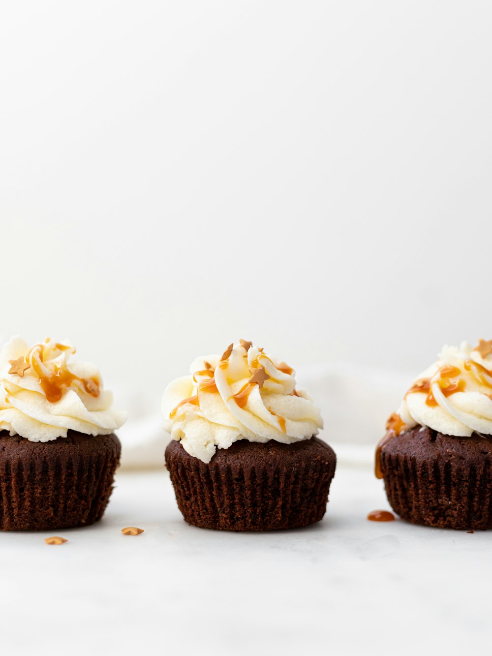 Tres cupcakes sobre superficie blanca