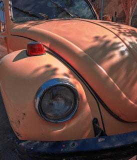 A close-up shot of a classic Volkswagen Beetle's round headlight gleaming under soft sunlight.