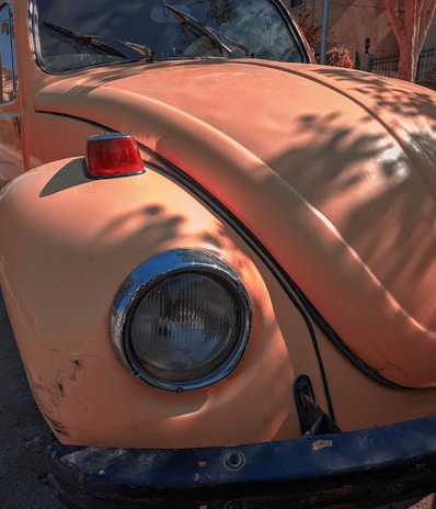 A close-up shot of a classic Volkswagen Beetle's round headlight gleaming under soft sunlight.