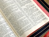 An open page of a book displaying text from the Bible, specifically Psalms. The pages have a classic, slightly yellowed appearance with text organized into columns. The book has a black cover with a red and gold spine, indicating it might be of high quality or a special edition.