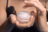 person holding white and pink round plastic container