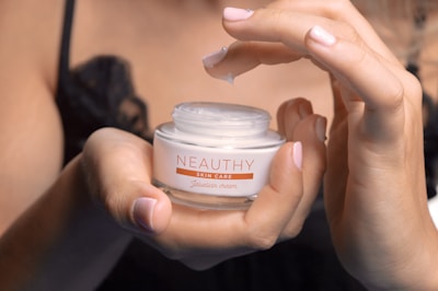person holding white and pink round plastic container