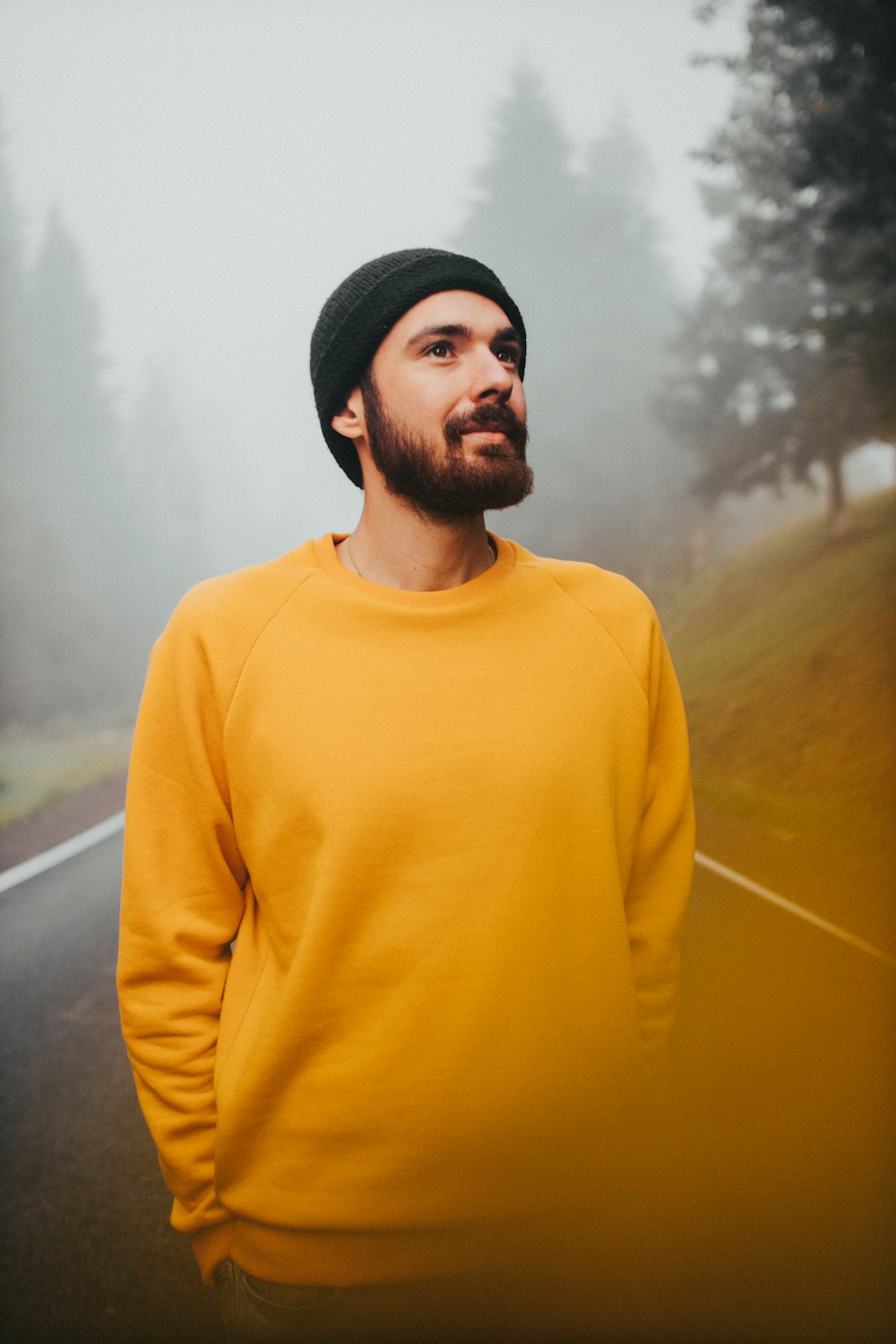 man in yellow turtleneck sweater standing near green grass field