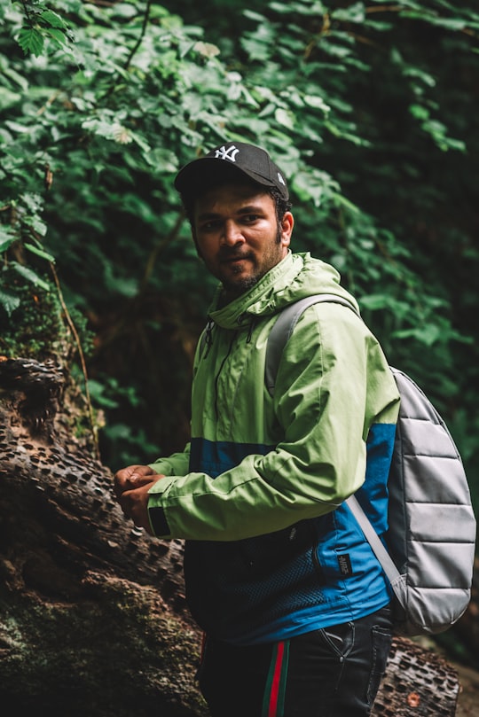 man in green jacket and black cap standing near green trees during daytime in Wales United Kingdom