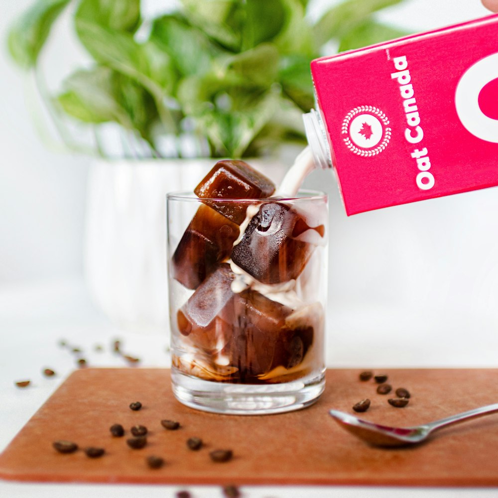 clear drinking glass with brown liquid on brown wooden chopping board