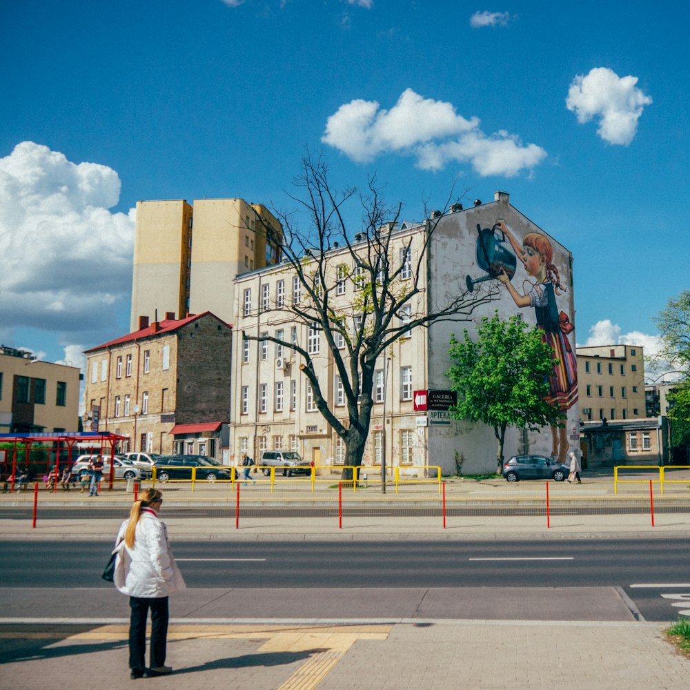 woman in white coat walking on sidewalk during daytime