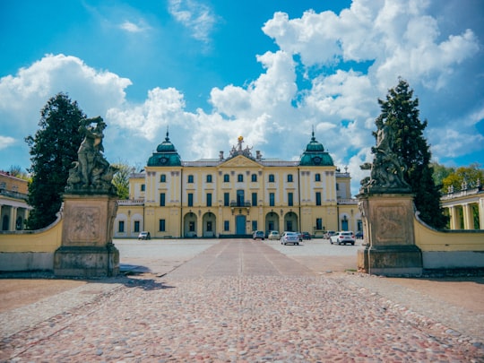 brown and white concrete building under blue sky and white clouds during daytime in Branicki Palace Poland