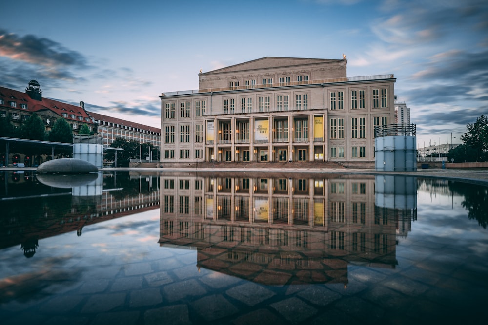 Bâtiment en béton blanc près d’un plan d’eau pendant la nuit