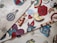 A collection of fabric swatches featuring various colorful designs. The patterns include a stylized hot air balloon, a rose, a rainbow, yin-yang symbol, pizza slice, a heart with flames, vintage cars, and other assorted graphics. The designs are vibrant and eclectic, with a mix of traditional and pop culture elements.