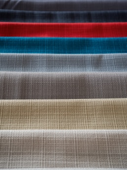 A collection of fabric swatches featuring different colors arranged in parallel rows. The fabric has a textured, woven pattern that gives each swatch a unique appearance.